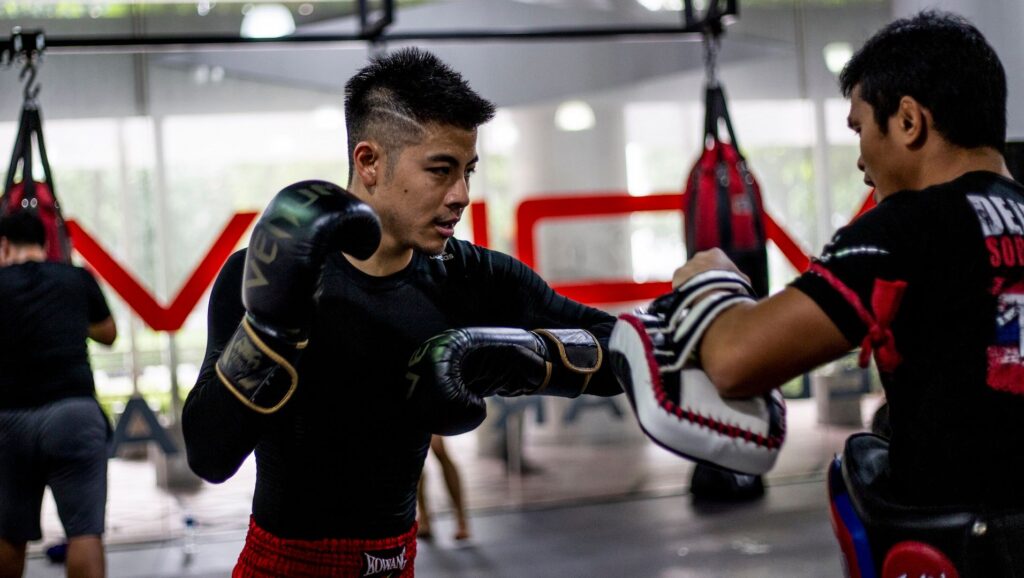 A Muay Thai student throws an elbow at a pad